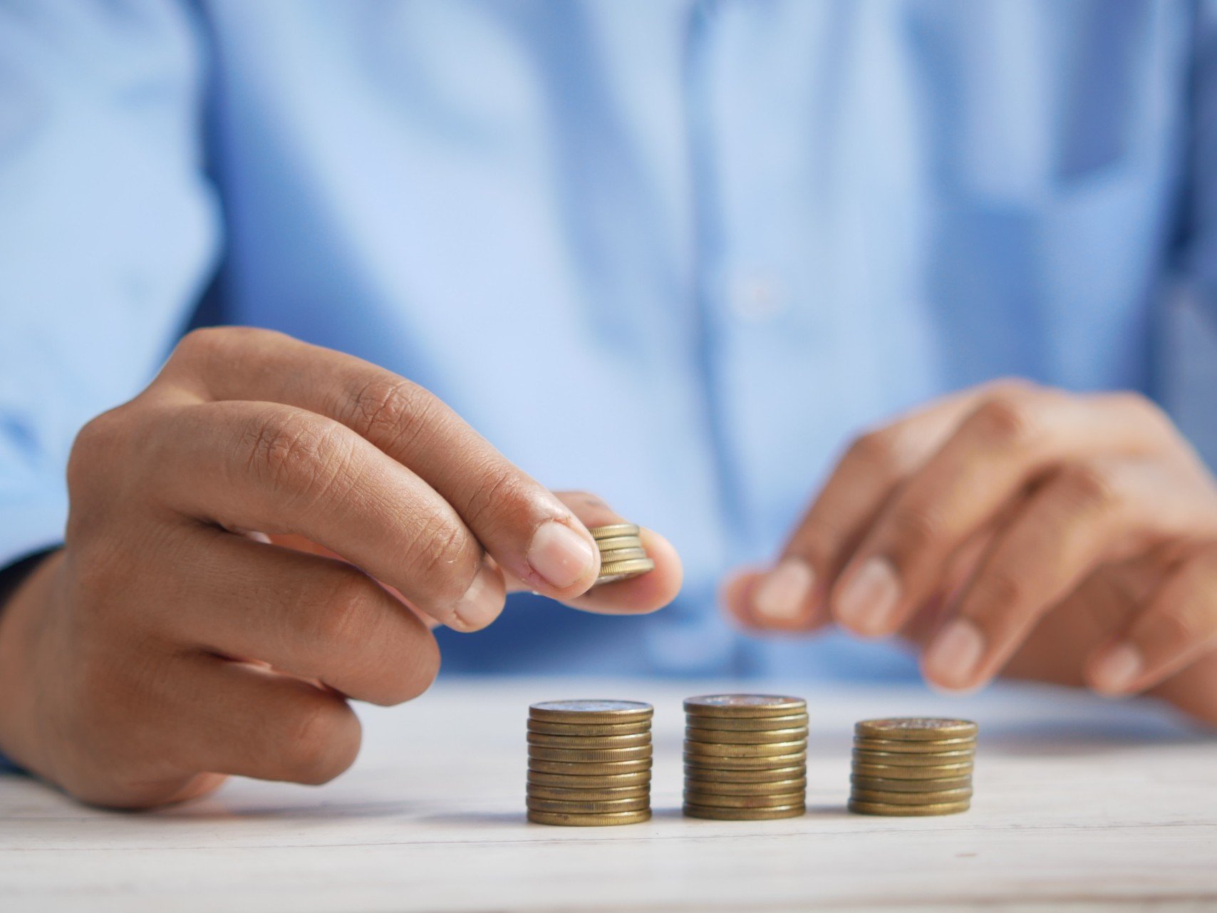 A person stacking coins into descending piles