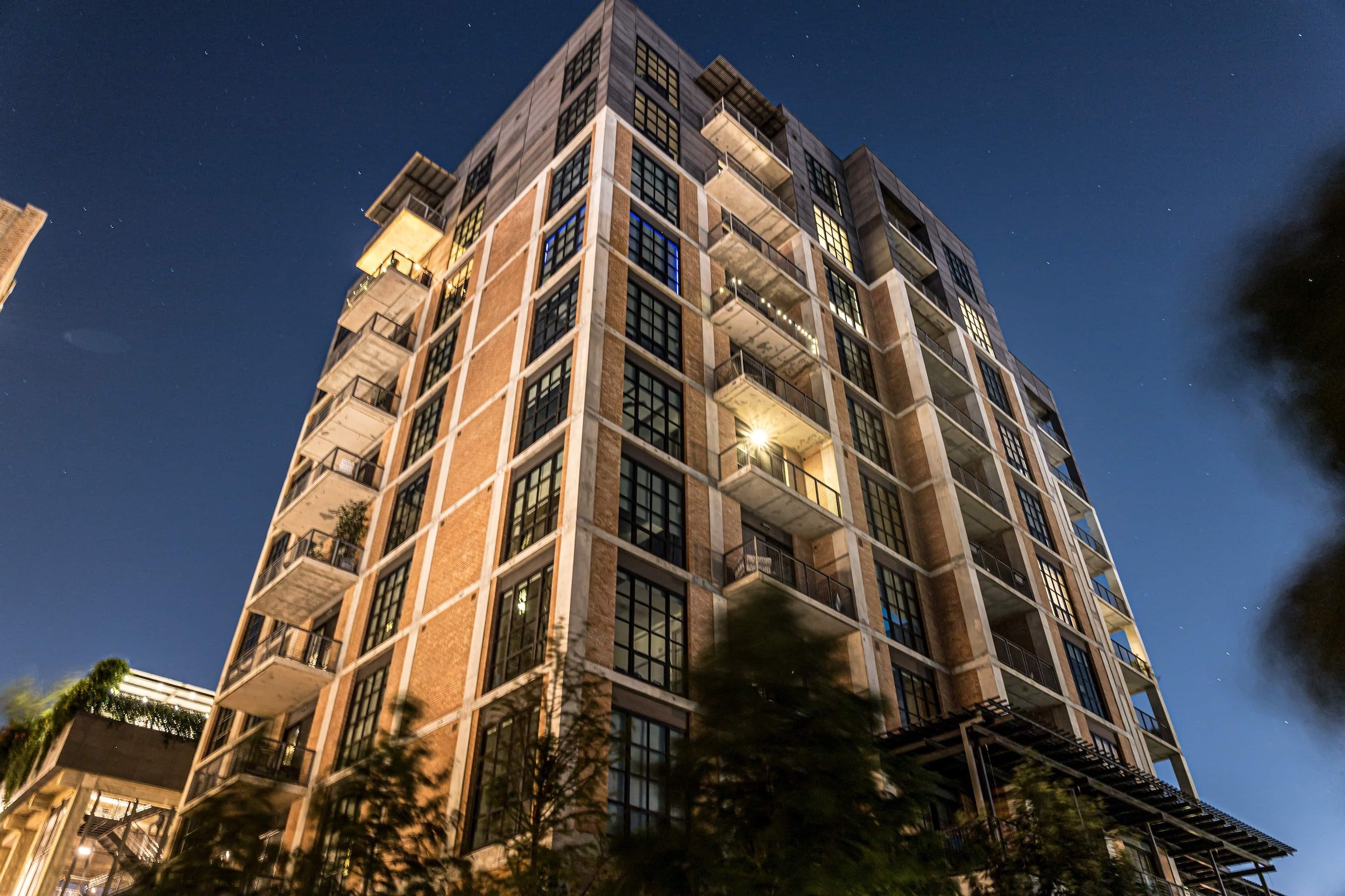 Image of high rise condominium from the street level. A mid-rise apartment building lit up at dusk