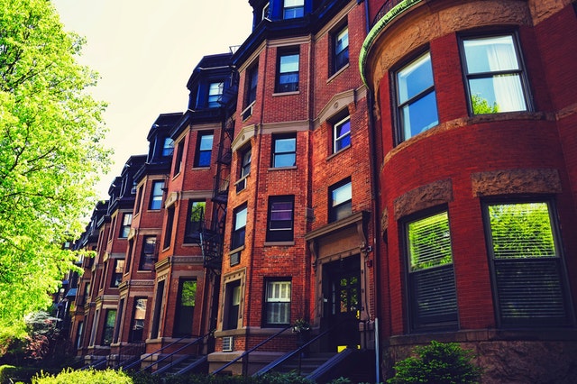 A row of brick brownstone apartment buildings on a tree-lined street